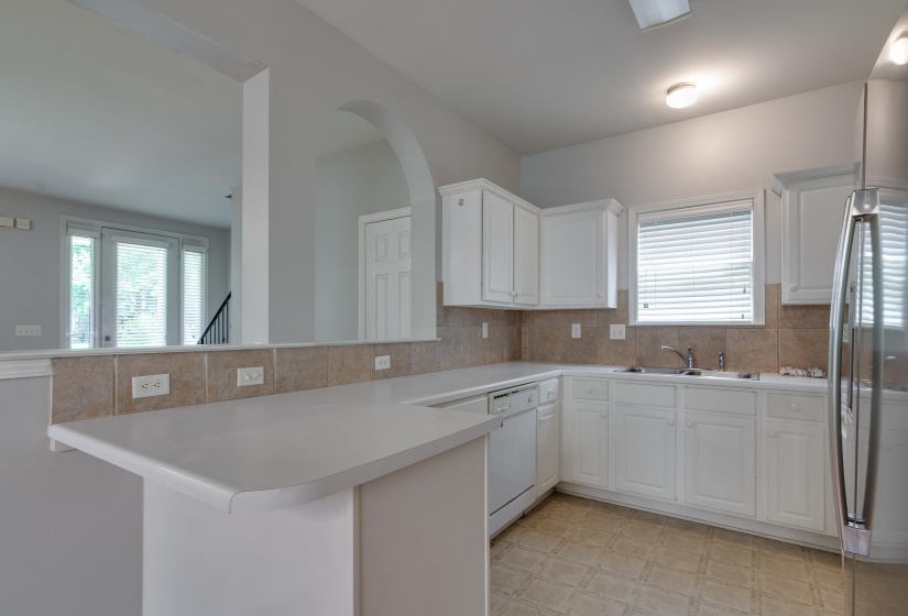 Kitchen featuring white cabinetry, light-toned countertops, a tile backsplash, and stainless steel appliances