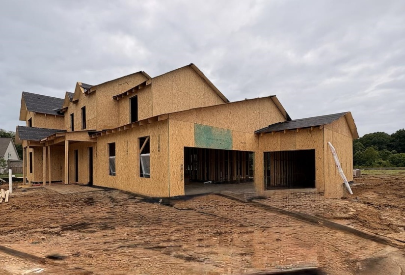 New construction framing with multiple dormers and a covered porch