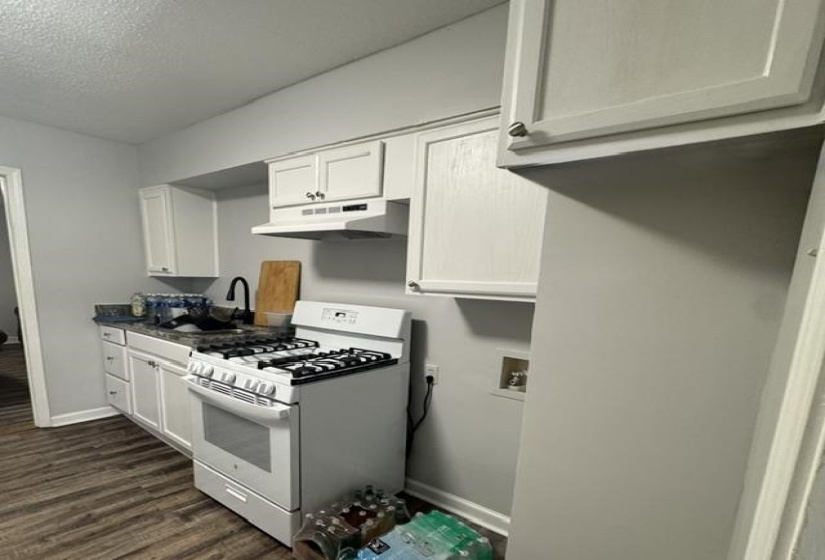 Kitchen featuring white cabinetry, dark countertops, a gas range, and a black gooseneck faucet