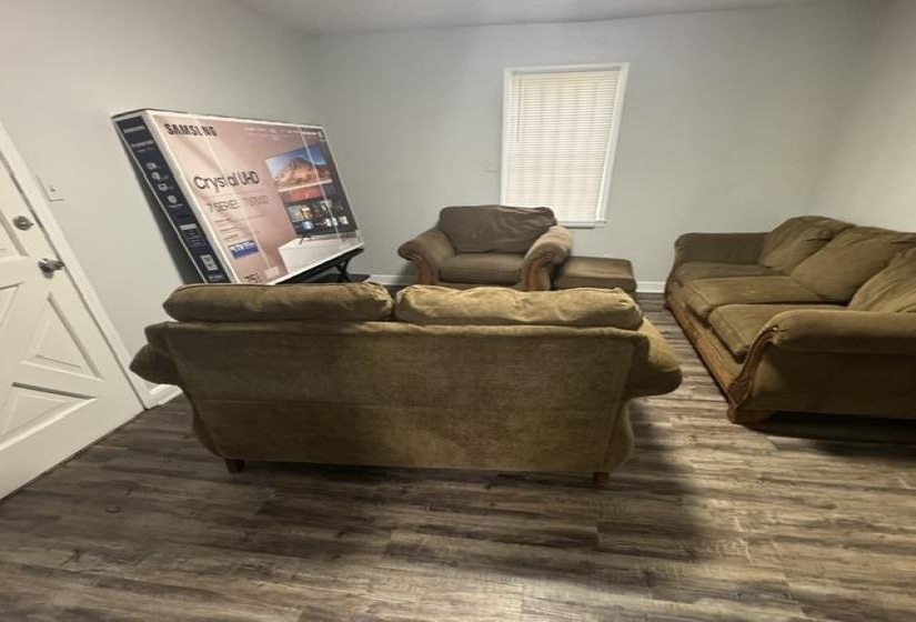 Spacious interior room featuring wood-finish flooring, light gray wall paint, and a window with blinds