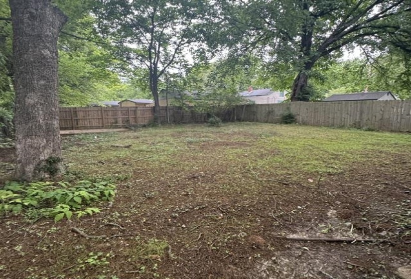 Expansive rear yard featuring mature trees and wood privacy fencing