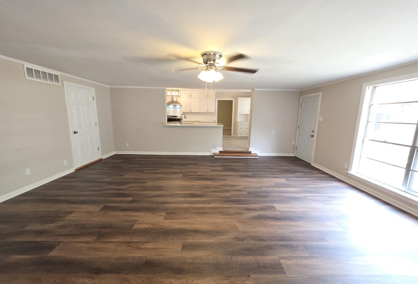 Spacious living area featuring wood-finish flooring, neutral wall tones, and crisp white trim