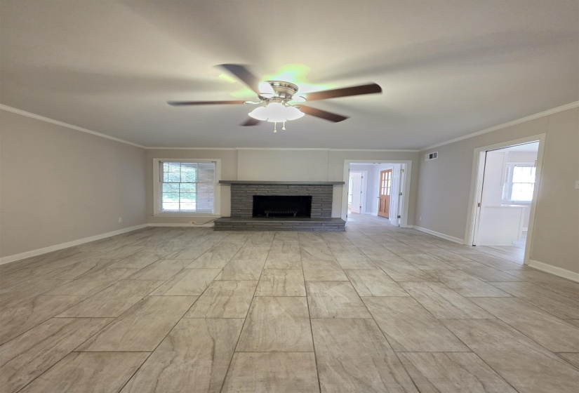 Spacious room featuring wood-look plank tile flooring, a stone-clad fireplace with a raised hearth, and neutral wall tones