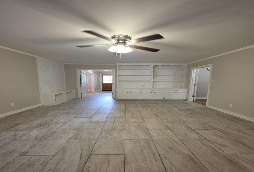 Spacious interior featuring plank-style tile flooring, built-in shelving, a ceiling fan with integrated lighting, and white baseboards