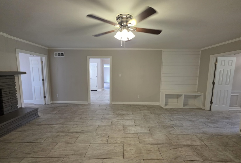 Spacious interior featuring large format tile flooring, a stone-clad fireplace with mantel, and a built-in storage bench with shiplap accent wall