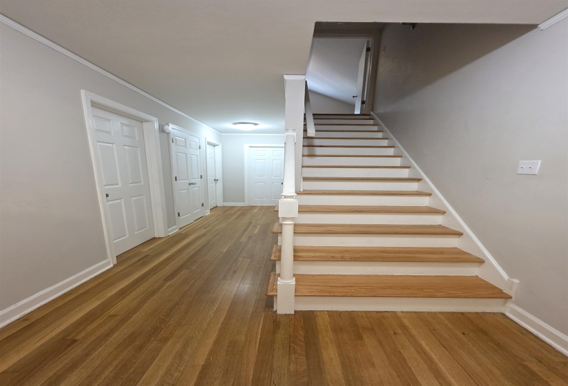 Staircase with light wood-finish treads and white risers, complemented by a white handrail and balusters