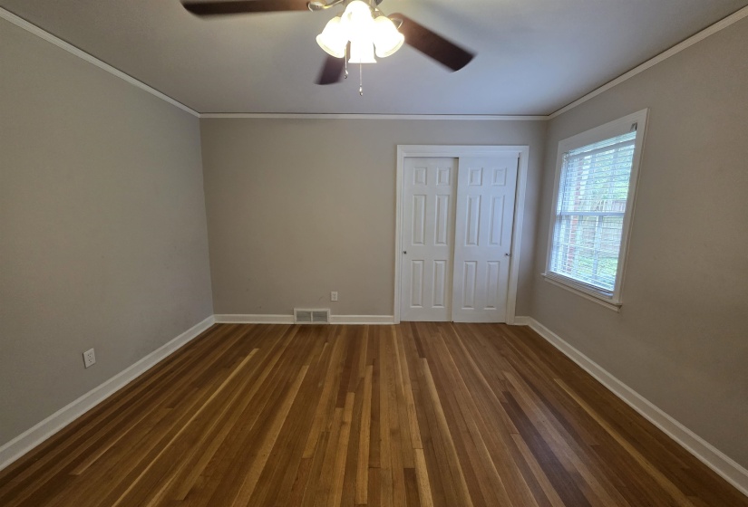 Hardwood flooring, neutral wall tones, white trim, sliding closet doors, and ceiling fan with lighting