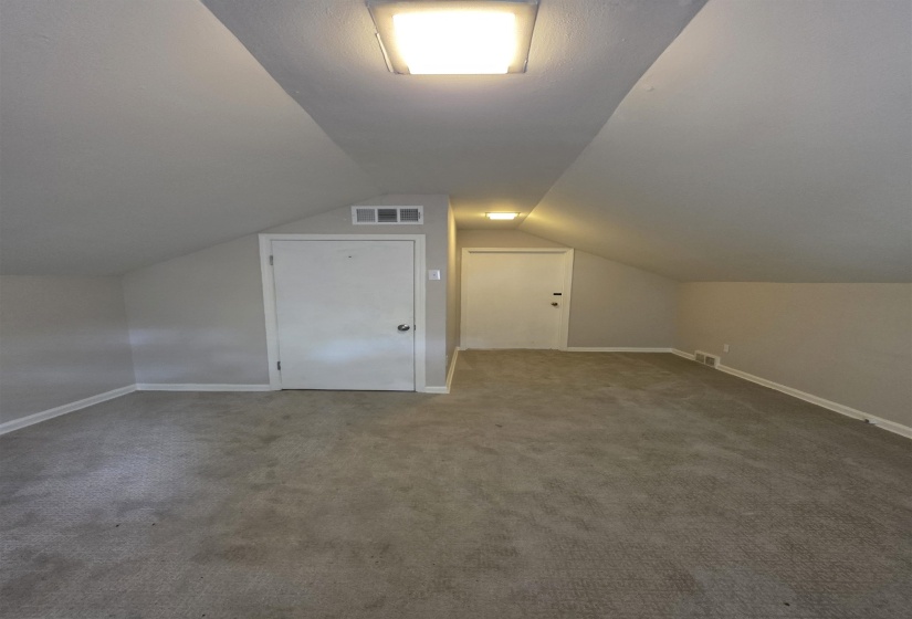 Carpeted room with sloped ceilings and recessed lighting