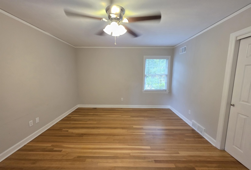 Bright room featuring wood-finish flooring and a ceiling fan with integrated lighting
