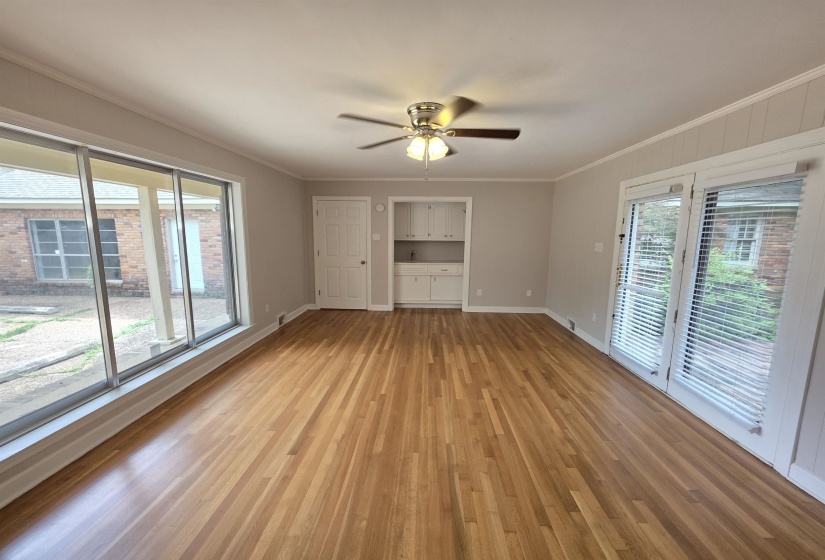 Expansive interior space featuring wood-finish flooring, a ceiling fan, and large picture windows