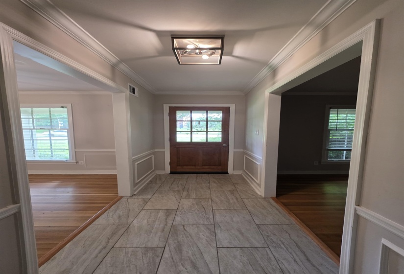 Entry foyer featuring wood-finish tile flooring and a dark wood entry door with glass panes