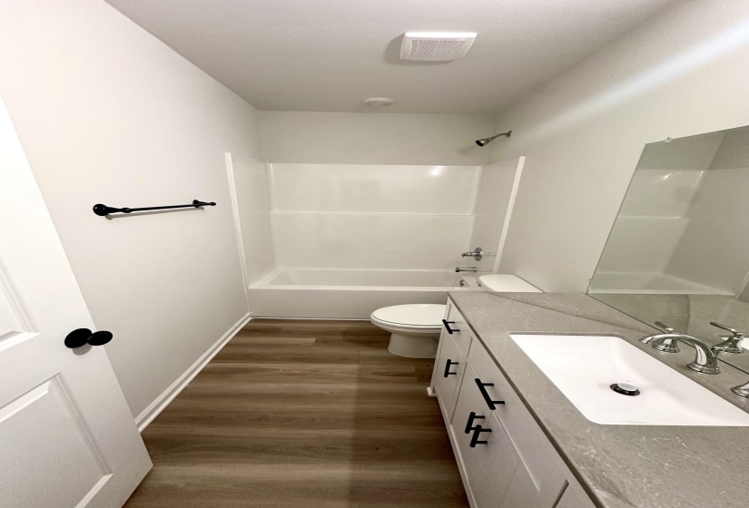 Contemporary bathroom featuring a white vanity with black hardware, a light gray countertop, and a rectangular undermount sink