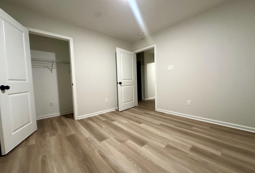 Spacious room featuring wood-finish flooring, white baseboards, and neutral wall tones