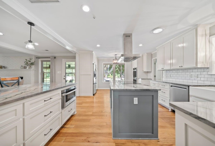 Kitchen featuring a large central island with a contrasting base, white cabinetry, stainless steel appliances, and tile backsplash.