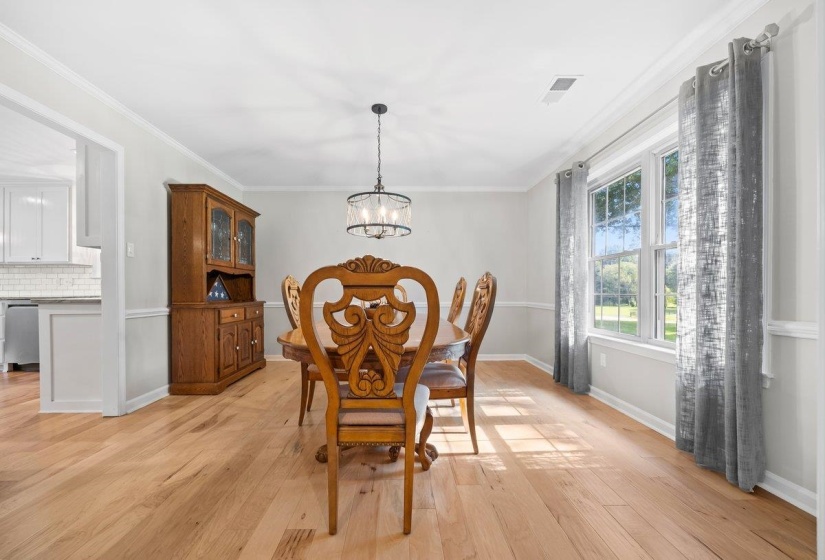 Bright room featuring wood-finish flooring, white crown molding, and a chandelier