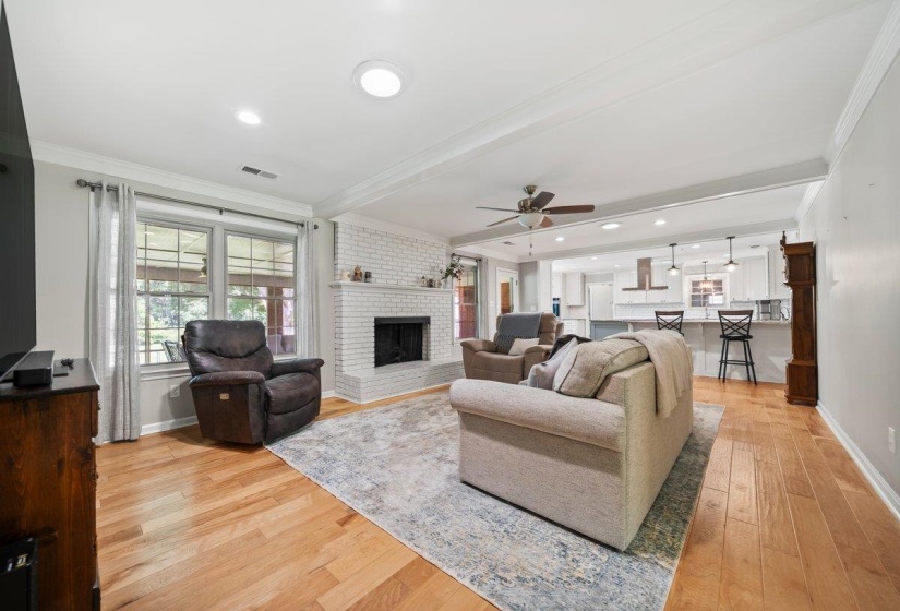 Open-concept Den area featuring wood-finish flooring and a white brick fireplace