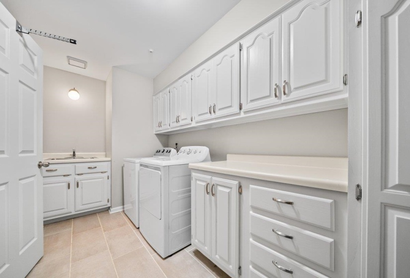 Laundry room featuring white cabinetry, light-colored countertops, and tiled flooring