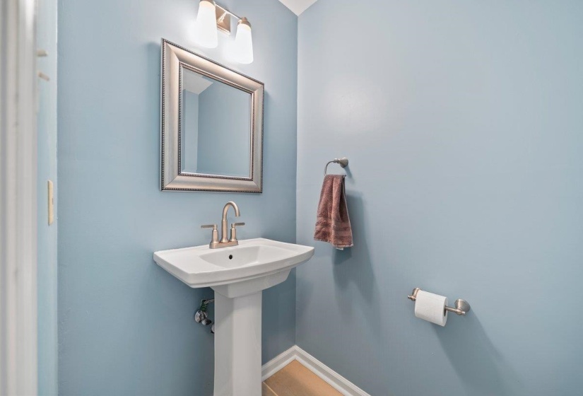 Pedestal sink with brushed nickel faucet, framed mirror