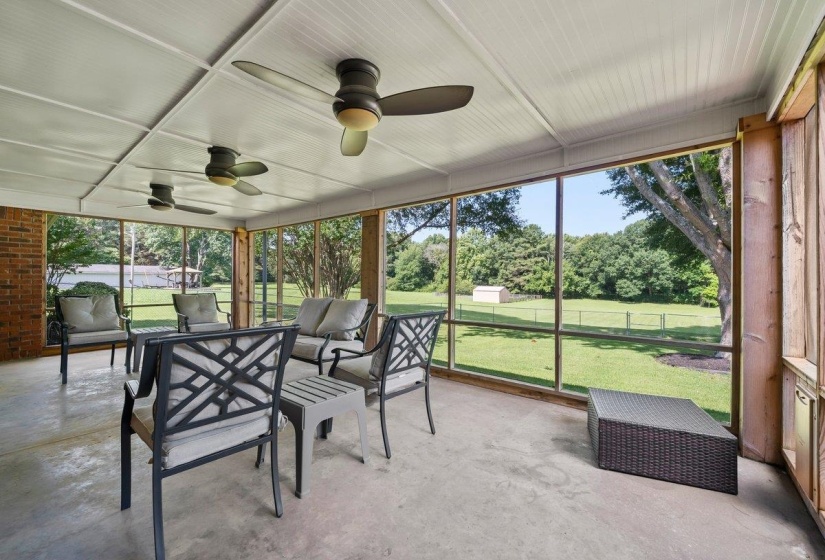 Screened porch featuring a concrete floor and beadboard ceiling with multiple ceiling fans