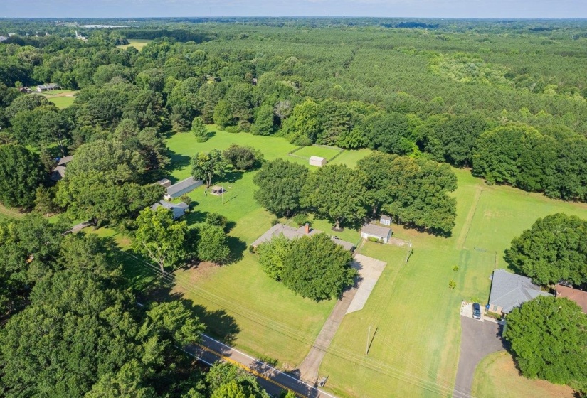 Expansive property featuring a verdant landscape, mature trees, and a distant treeline