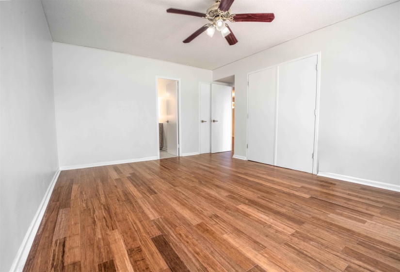 Room featuring wood-finish flooring, white walls, and a ceiling fan with light fixture