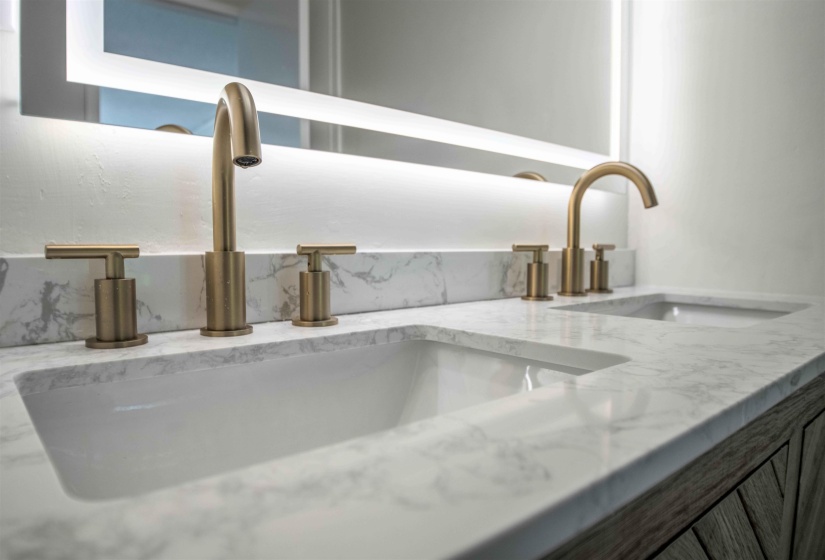 Dual undermount sinks set within a white countertop with gray veining
