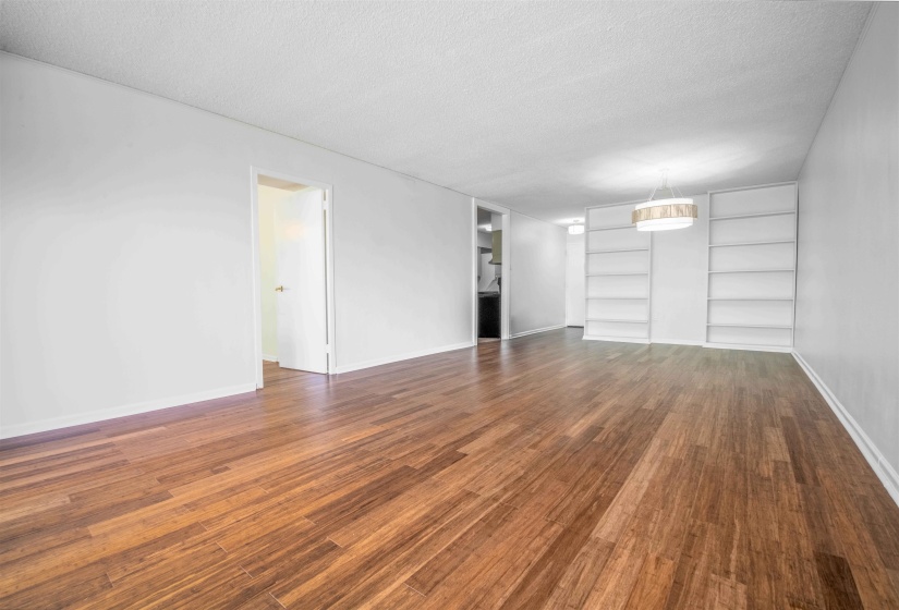 Expansive room featuring wood-finish flooring, white walls, and built-in shelving