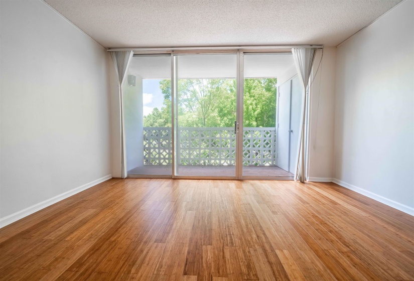 Bright interior space featuring wood-finish flooring, white walls, and a sliding glass door opening to a private balcony