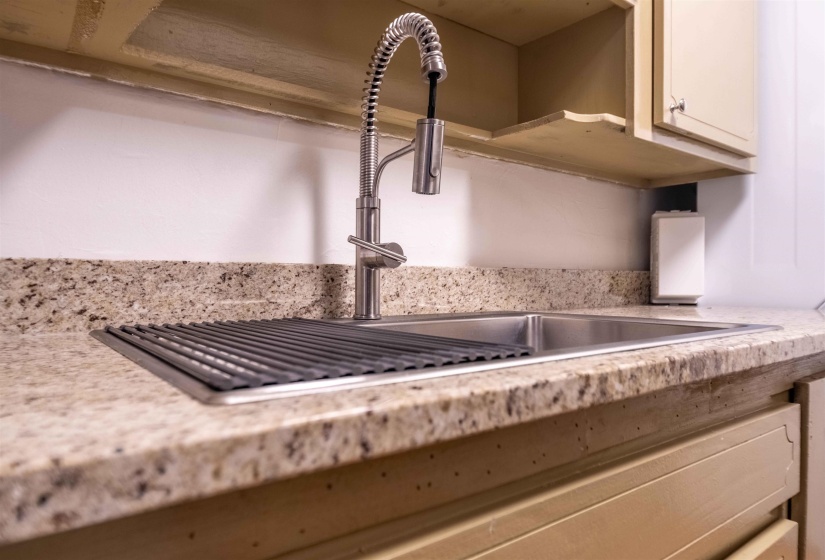 Stainless steel sink with an integrated drying rack, complemented by a contemporary pull-down faucet