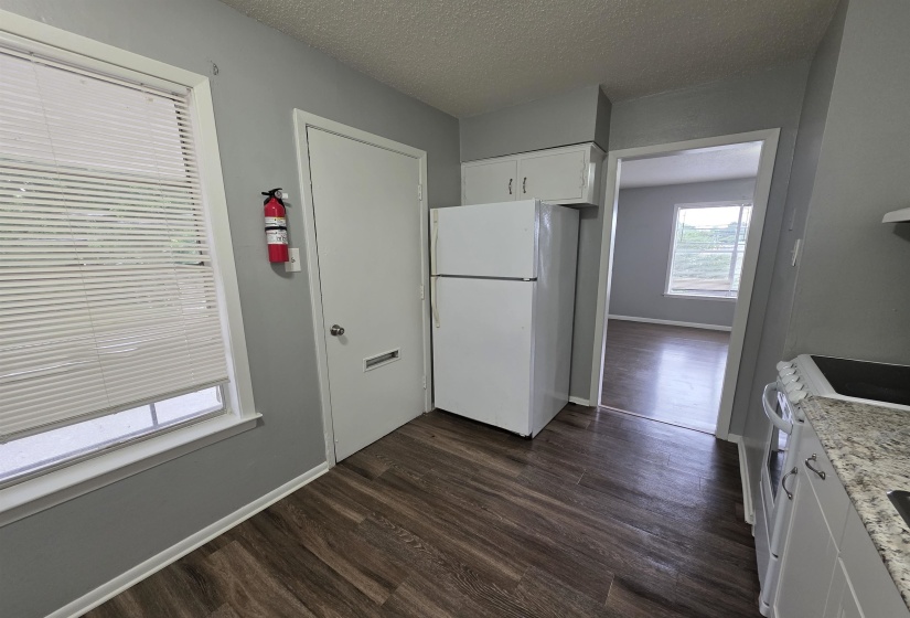 Kitchen area featuring wood-finish flooring, white cabinetry, a white refrigerator, and light-toned countertops