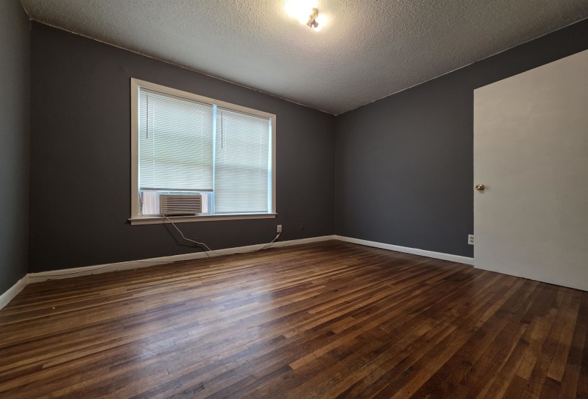 Room featuring wood-finish flooring, dark gray walls, and white trim