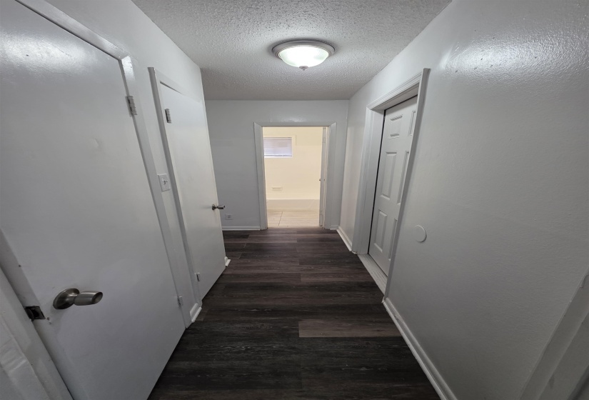 Hallway featuring wood-finish flooring, white walls, and a ceiling-mounted light fixture
