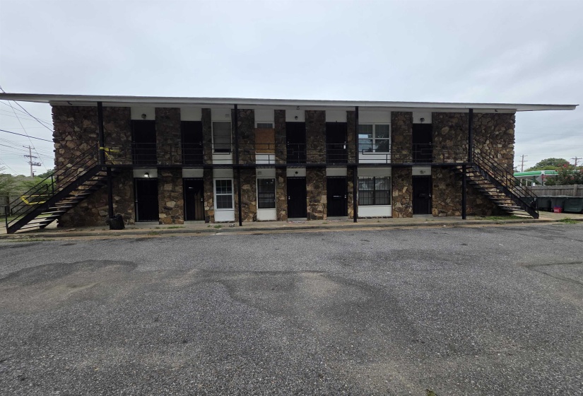 Two-story building featuring stone-clad facade, multiple entry points, and exterior staircases with metal railings