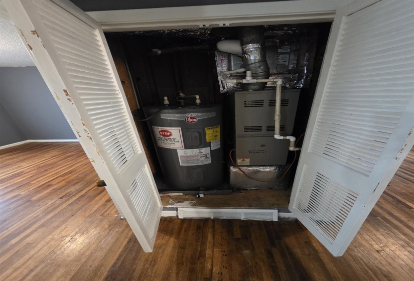 Utility closet featuring a water heater and furnace unit, framed by white louvered bifold doors