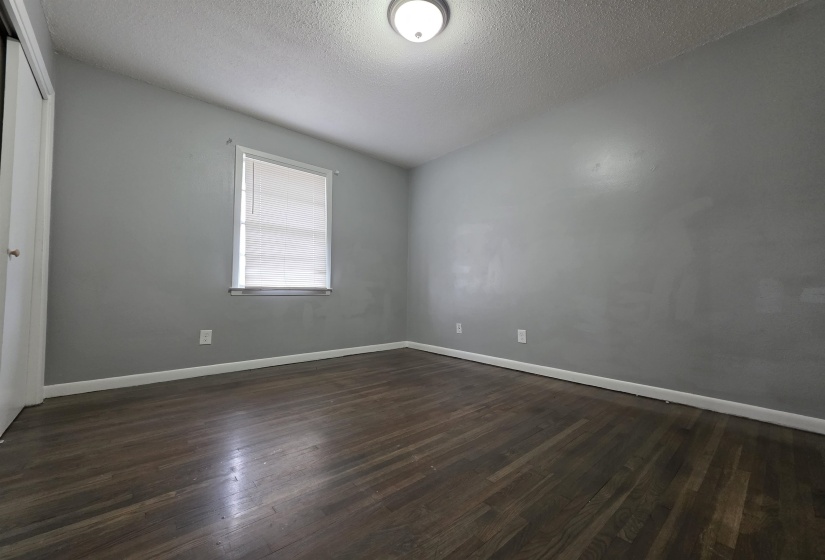 Room featuring wood-finish flooring, light grey painted walls, and a white trim baseboard