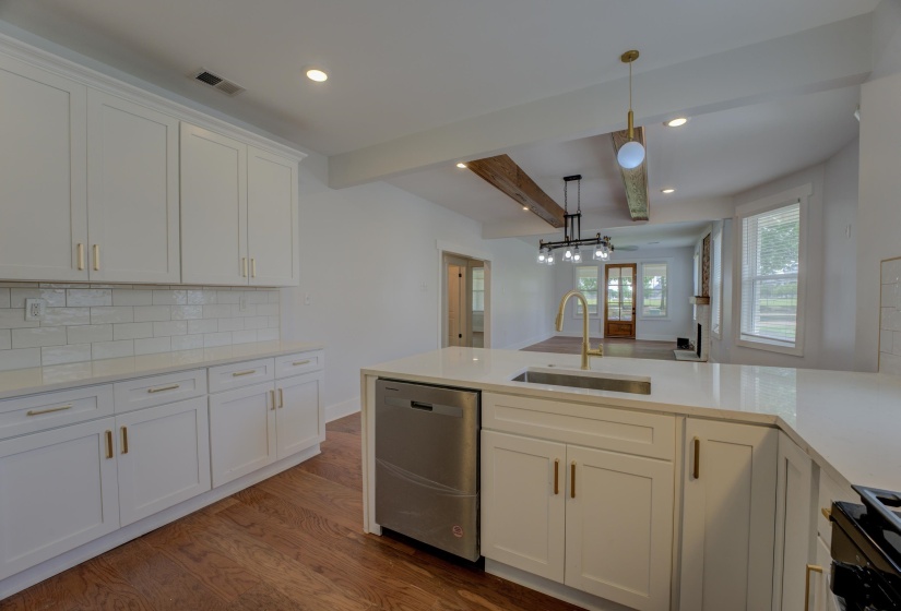 Well-appointed kitchen featuring white cabinetry with gold-finish hardware, subway tile backsplash, and light-toned countertops