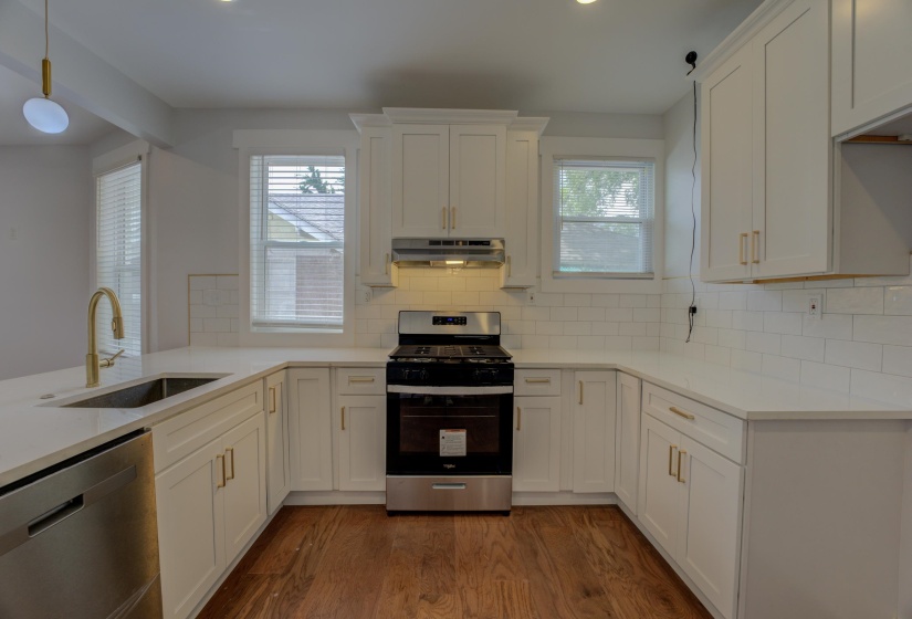 Modern kitchen with white shaker cabinetry, stainless steel range and dishwasher, light-toned countertops, and subway tile backsplash