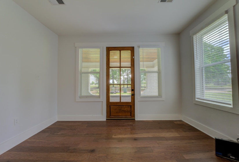 Entryway featuring a wood-finish door with glass panels, surrounded by white-framed windows with blinds