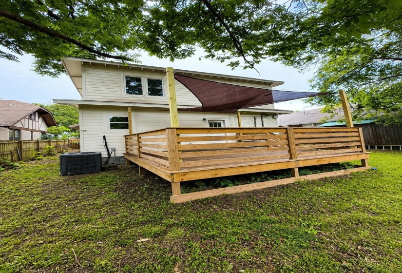 Expansive wooden deck featuring horizontal railings and a shade sail