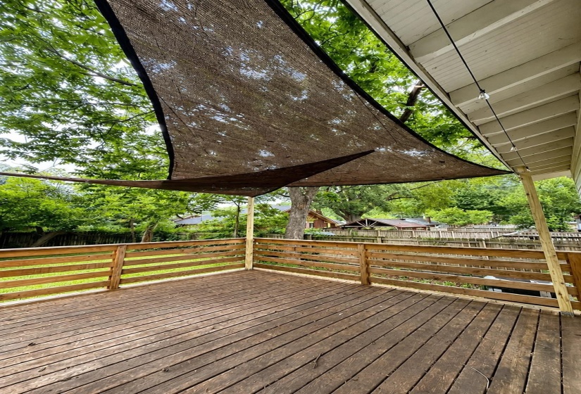 Expansive outdoor deck featuring wood-finish flooring, a slatted wood railing, and a large sunshade canopy