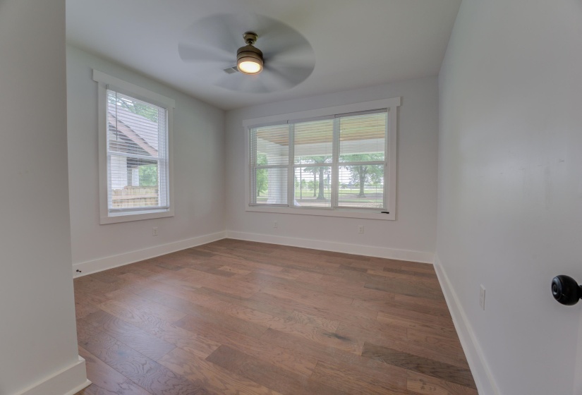 Bright room featuring wood-finish flooring, white baseboards, and a ceiling fan with integrated lighting