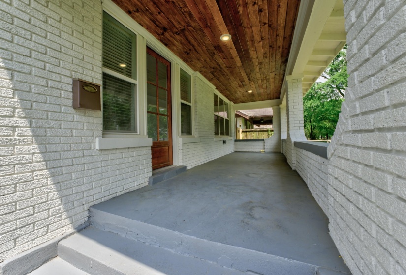 Front porch featuring painted brick exterior, wood-finish ceiling, recessed lighting, and a paneled wood-frame entry door