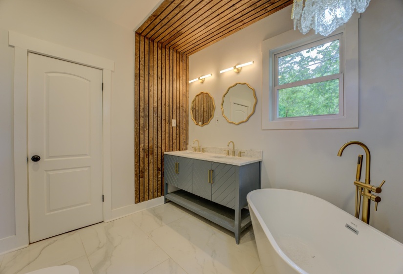 Freestanding soaking tub with a floor-mounted brass faucet