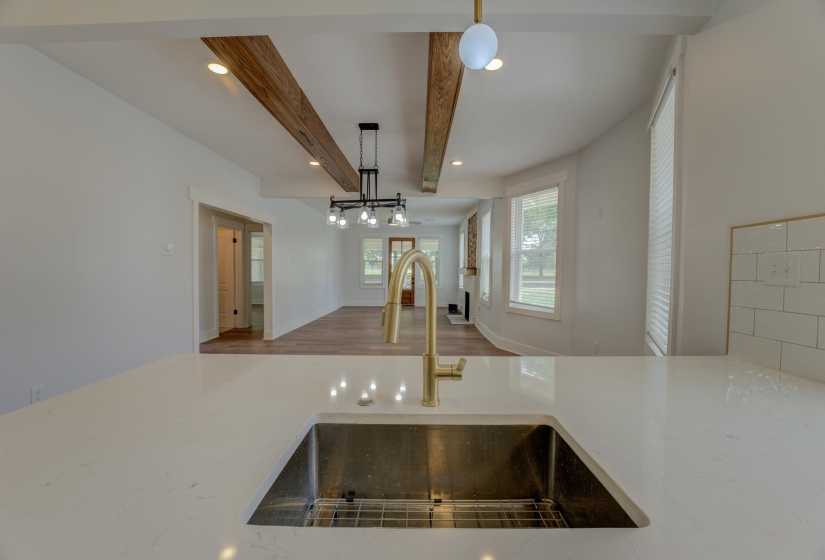 Spacious kitchen island featuring a stainless steel undermount sink, brass-finish faucet, and light-toned countertop