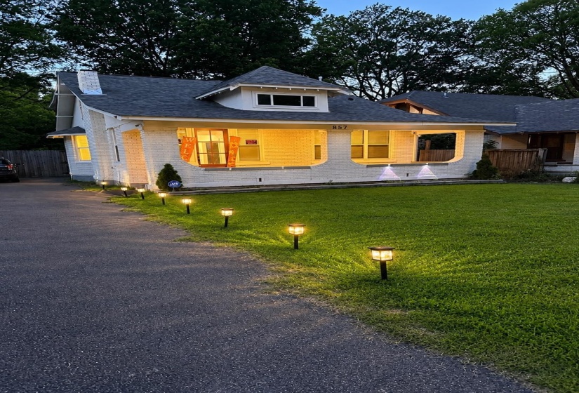 White brick exterior with a front porch, dormer window, and dark shingle roof