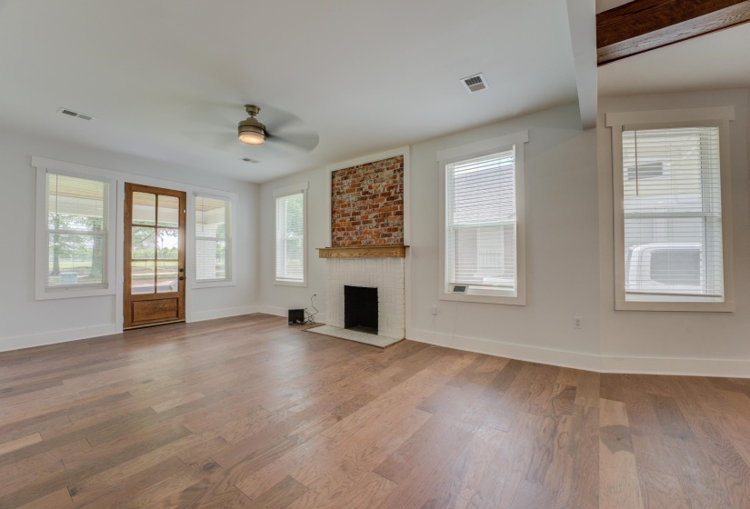 Spacious interior featuring wood-finish flooring, a ceiling fan, and multiple windows