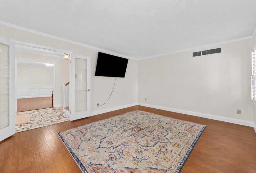 Large living room featuring beautiful flooring, neutral colors, and ample wall space for furniture placement. A versatile gathering area perfect for relaxing or hosting guests.