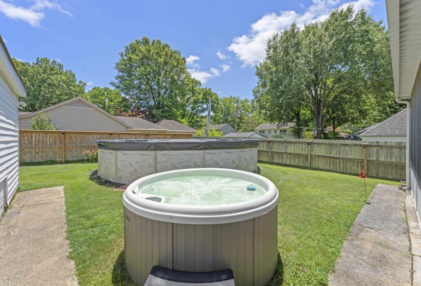 Fully fenced backyard offering plenty of room for recreation and relaxation. Features an above-ground pool, hot tub, mature trees, and open green space ideal for gatherings, pets, and outdoor enjoyment.