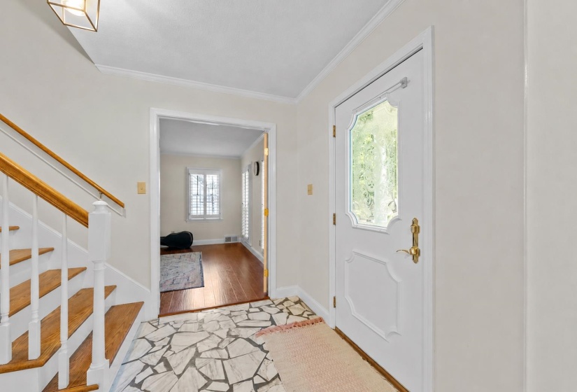 Inviting front entry featuring decorative glass front door, hardwood staircase, and a classic layout that creates a warm first impression.