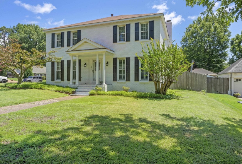 Stately painted brick exterior with mature landscaping and inviting covered entry creates a lasting first impression.